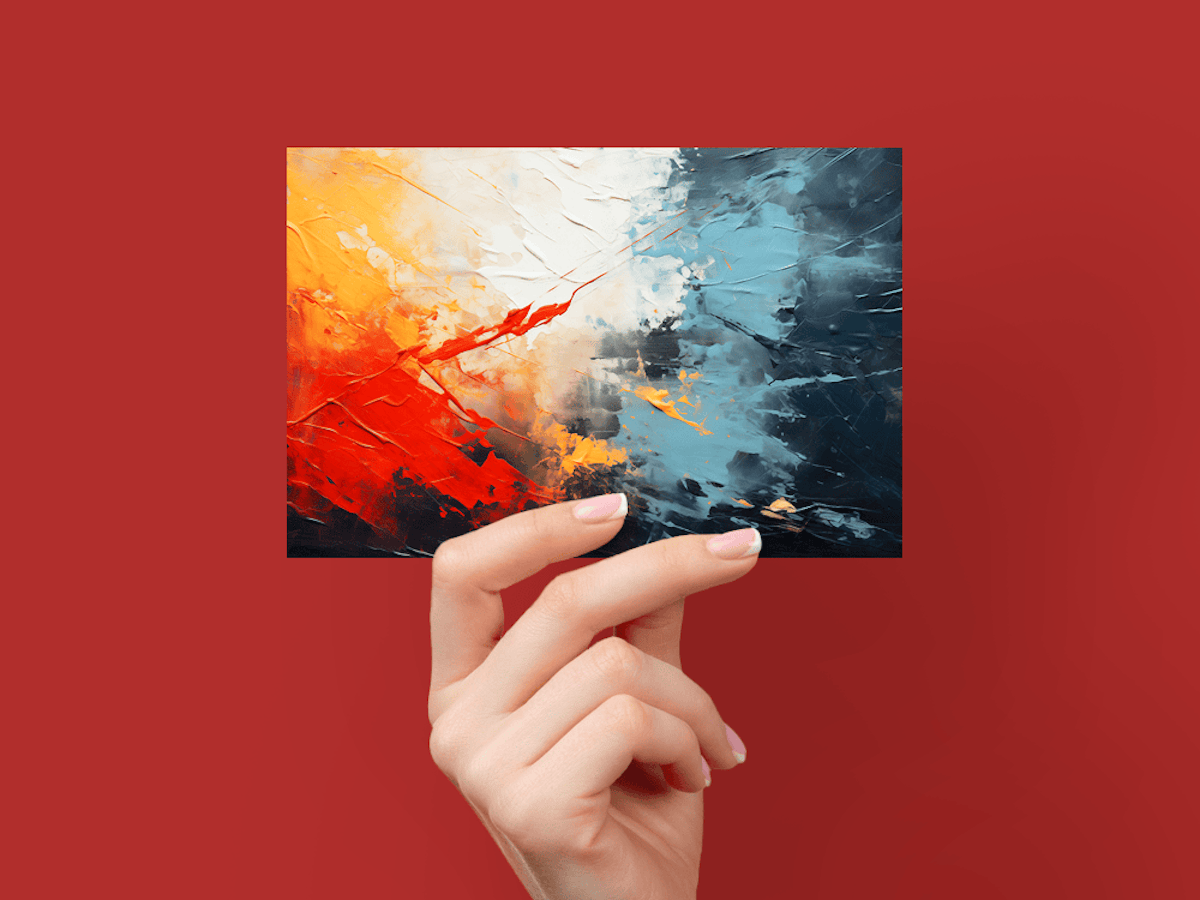 Hand holding card with abstract red, yellow, white, and blue paint splatter