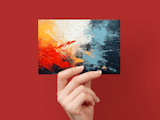 Hand holding card with abstract red, yellow, white, and blue paint splatter