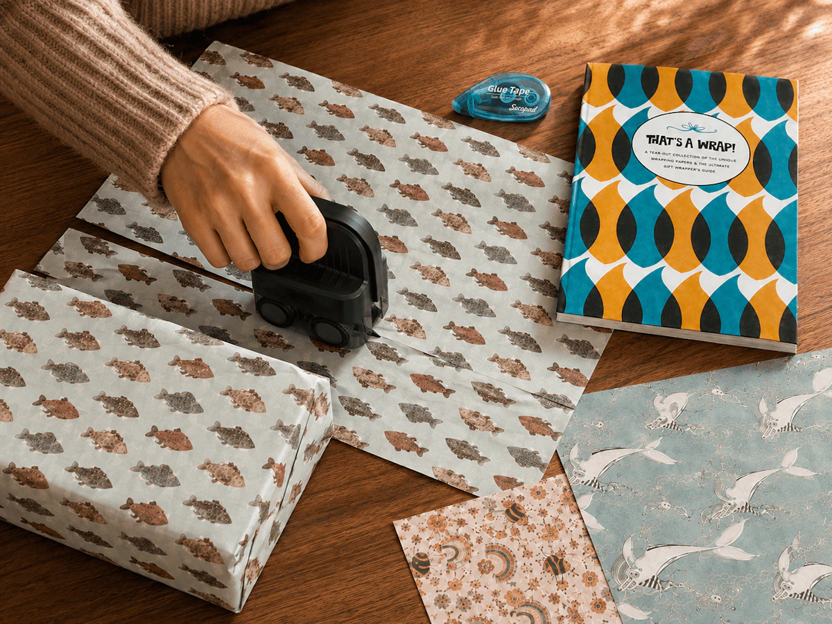 That's a Wrap book near hand taping up gift wrap with fish on it