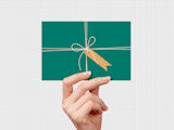 Hand holding card that looks like green present with white string bow and yellow tag