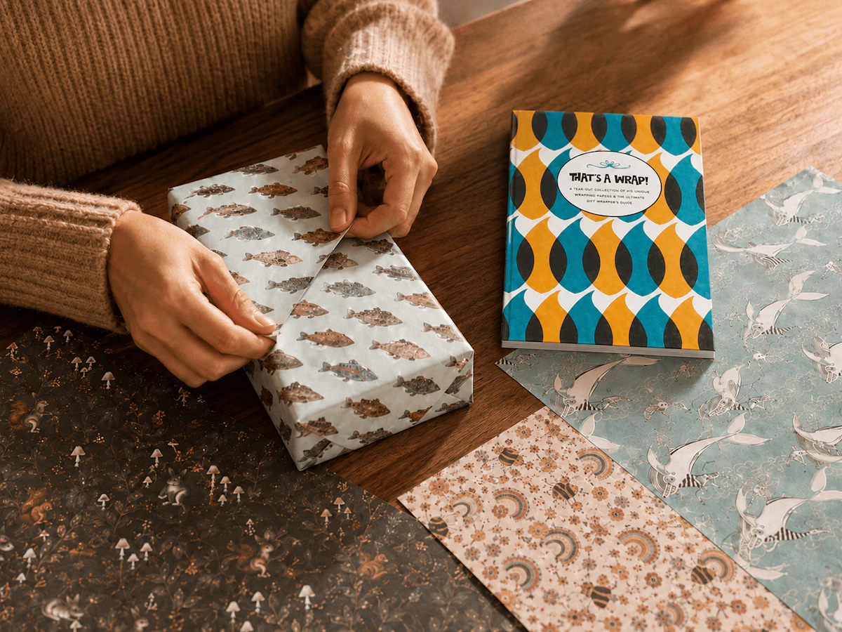 That's A Wrap book with arms in sweater wrapping a gift in fish wrapping paper