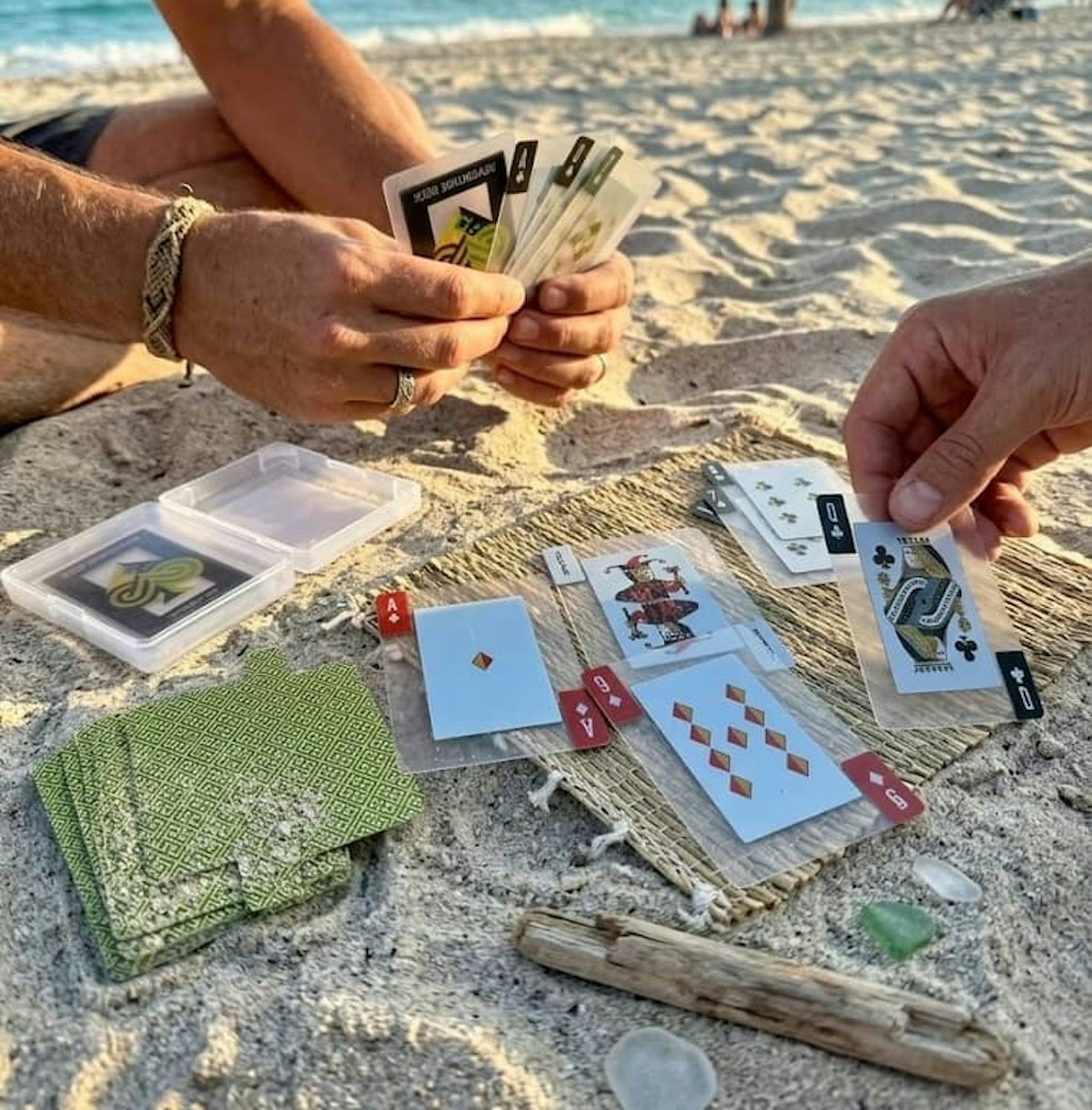 Card game on the beach showing only the players' hands.