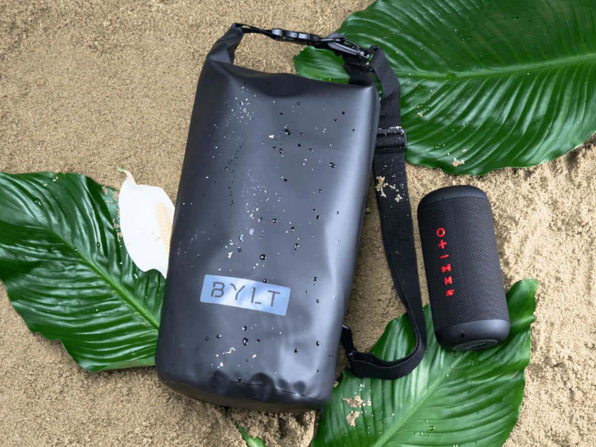 Wet Bylt Dry Bag and Speaker on ground with palm fronds